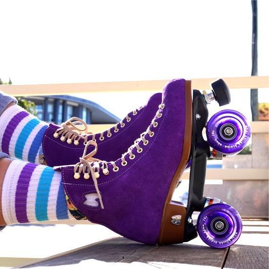 person wearing white mid calf socks with 3 blue and purple stripes and purple rollerskates