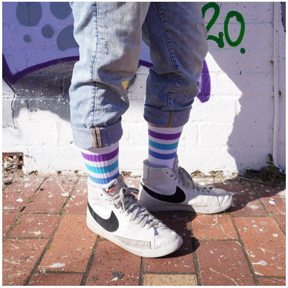 person wearing white mid calf socks with 3 blue and purple stripes and purple
