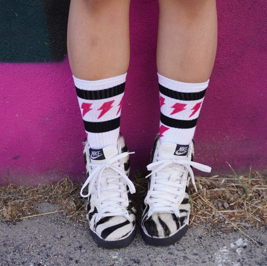 person wearing white mid calf socks with magenta lightinig bolts