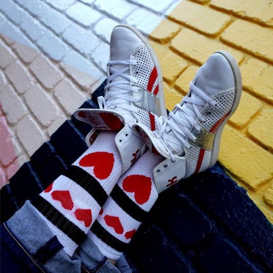 person wearing white mid calf socks with red love hearts and red white sneakers