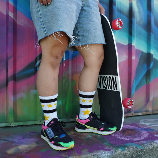 person wearing white mid calf socks with yellow stars and holding a skateboard