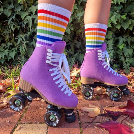 person wearing white mid calf socks with rainbow stripes and purple roller skates